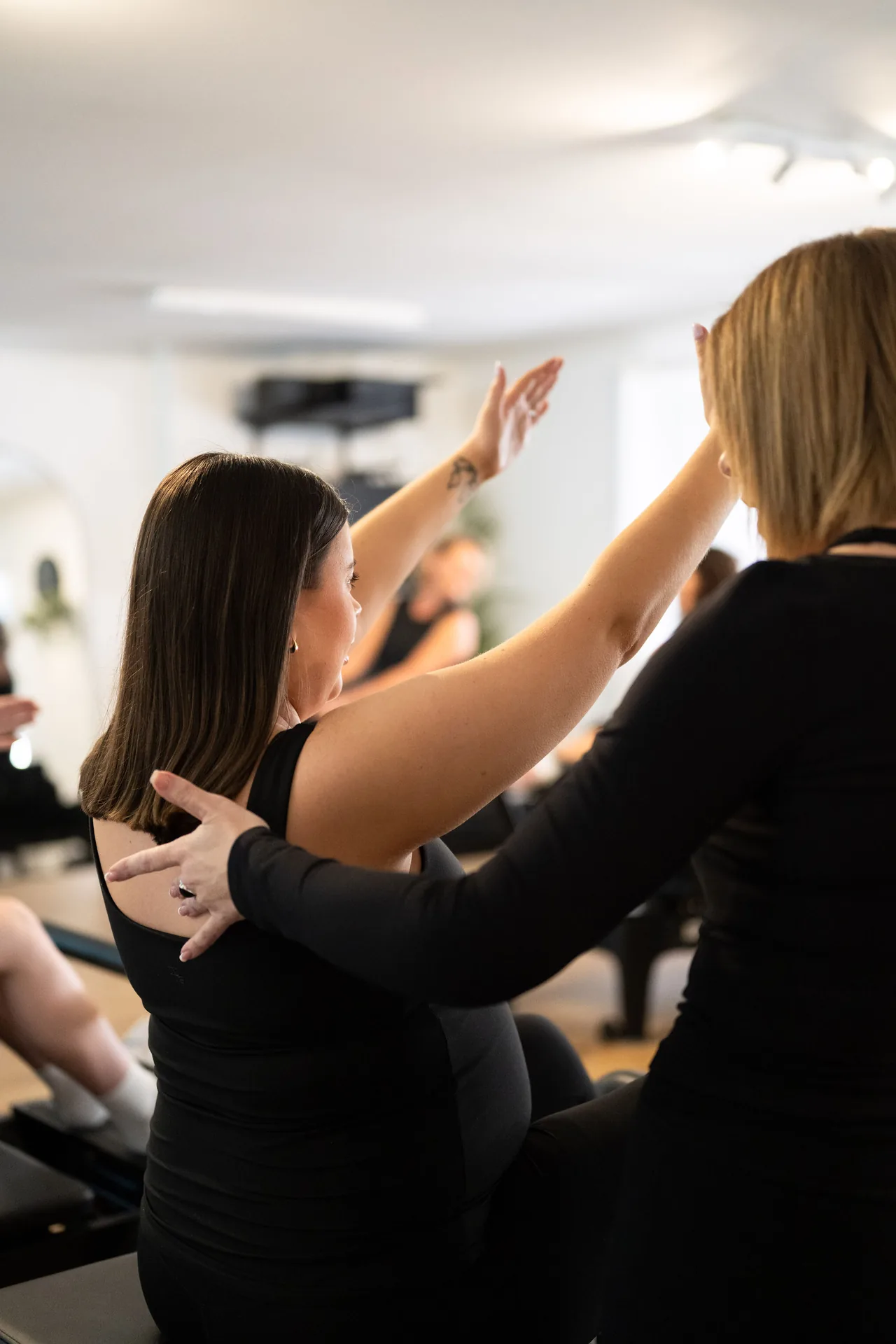 An instructor offering personal guidance during a Reformer Pilates class