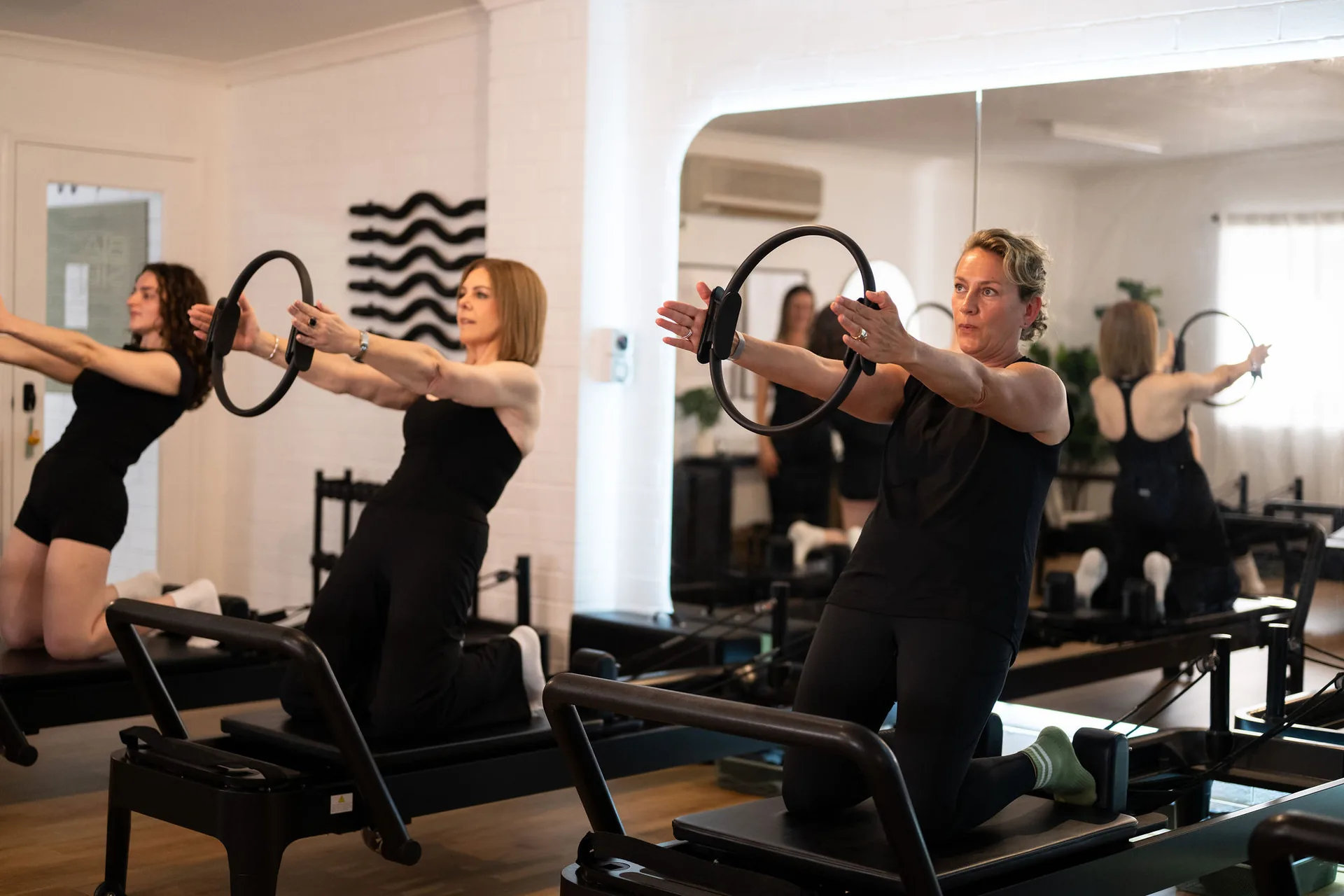 Women working with reformer straps during a stronger Pilates session